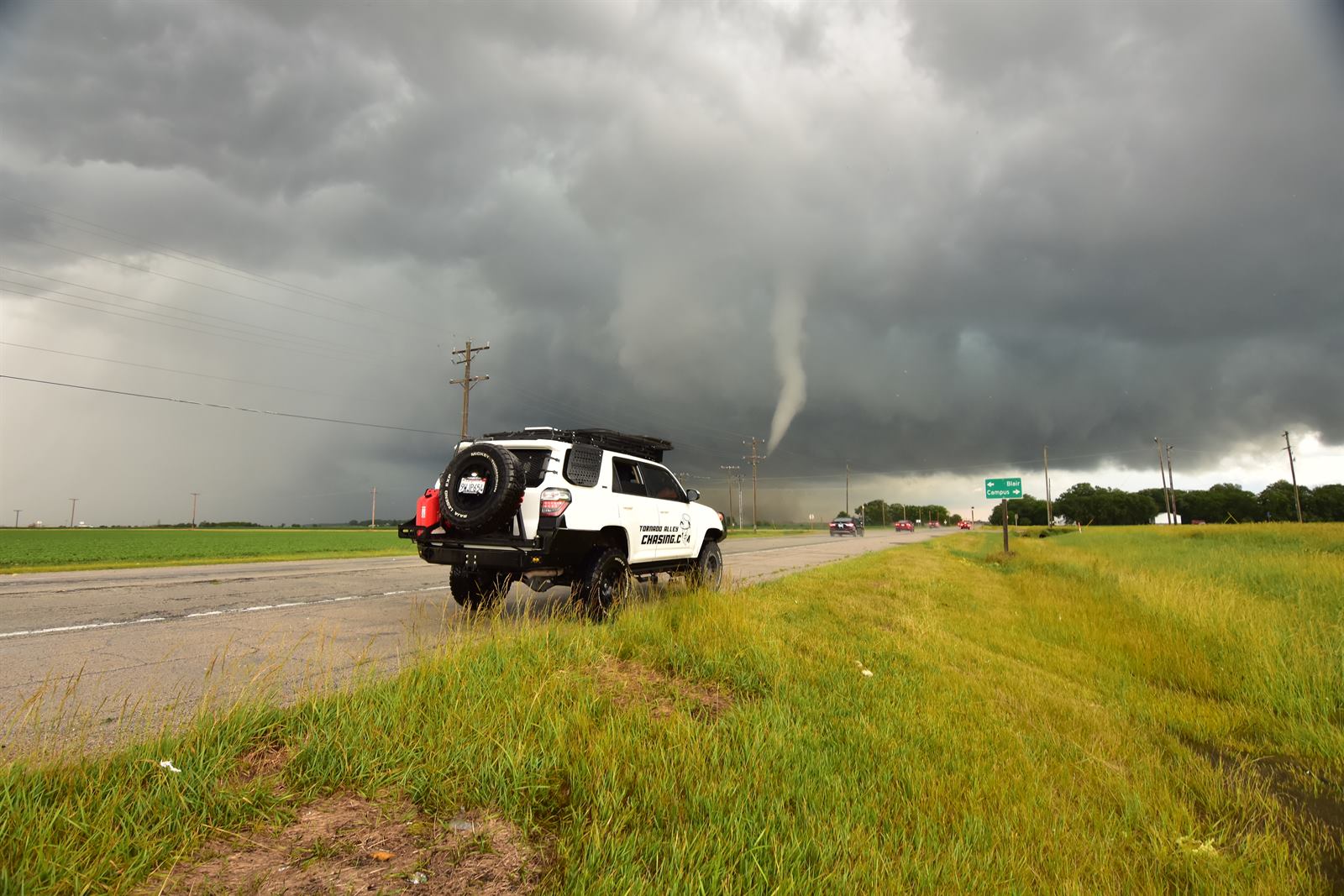 The chase vehicle parked with a tornado in the distance.