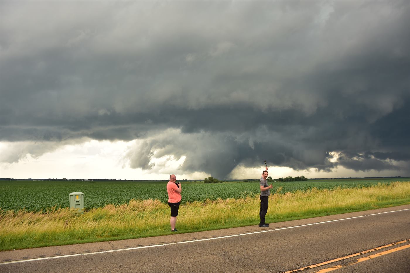 Standing in the field with a tornado on the ground behind.