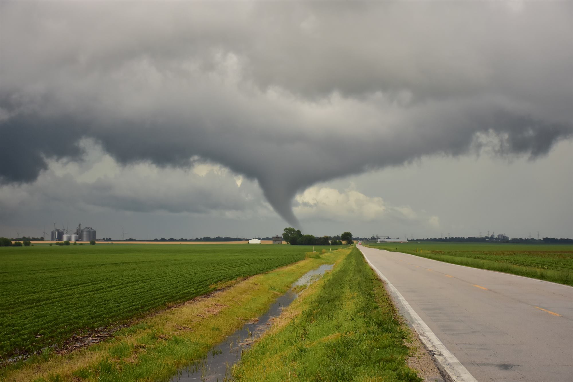 A cone tornado on the ground beneath a dark storm base.