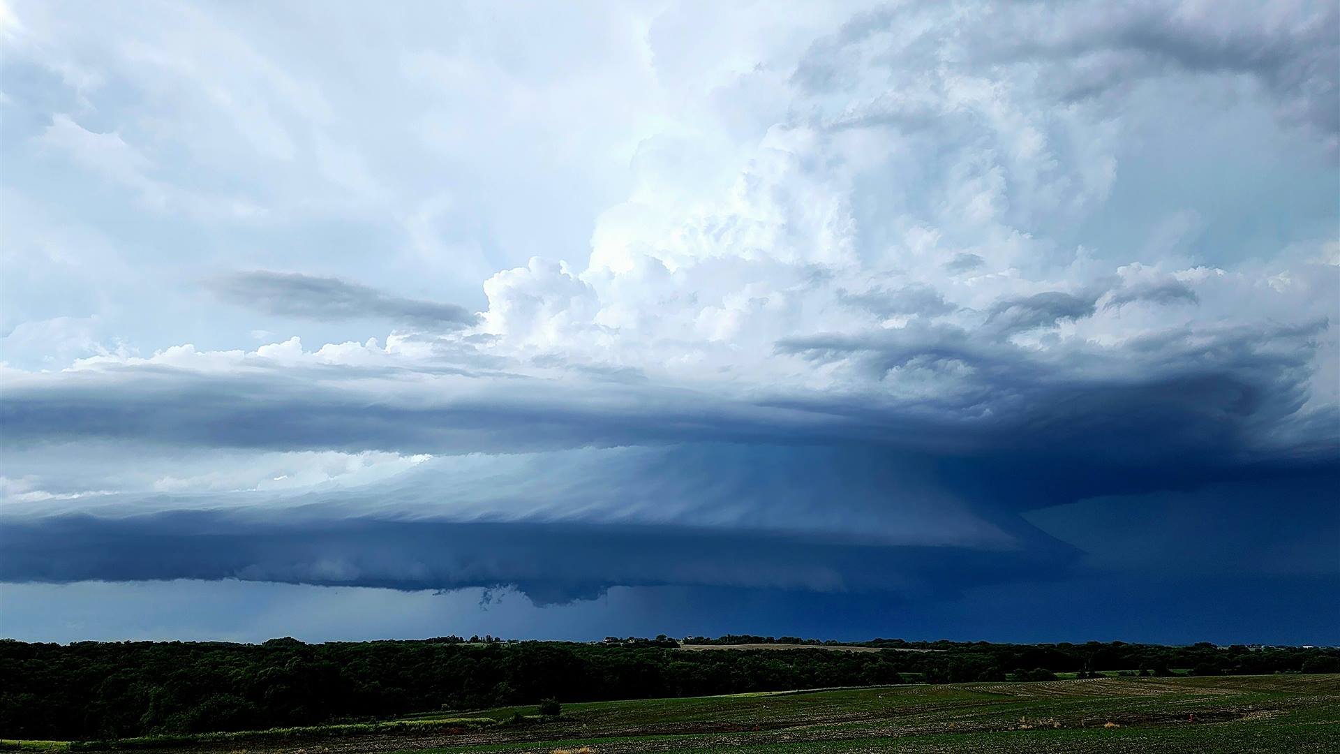 A supercell thunderstorm towering over open plains at dusk.